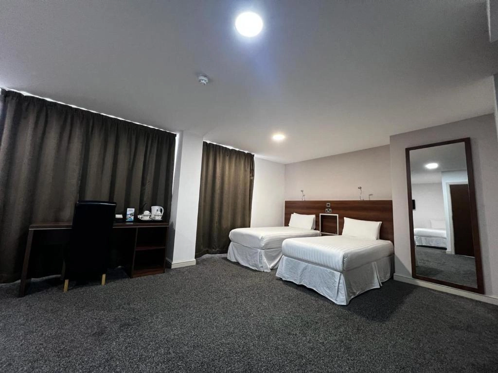 Twin guest room with desk and large mirror at Ox Hotel Manchester